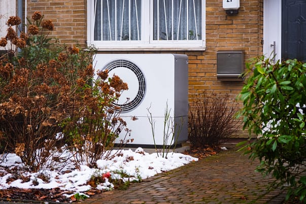 Lebensdauer Wärmepumpe Wärmepumpe im verschneiten Vorgarten nahe am Haus, die Lebensdauer beträgt ca. 20 Jahre