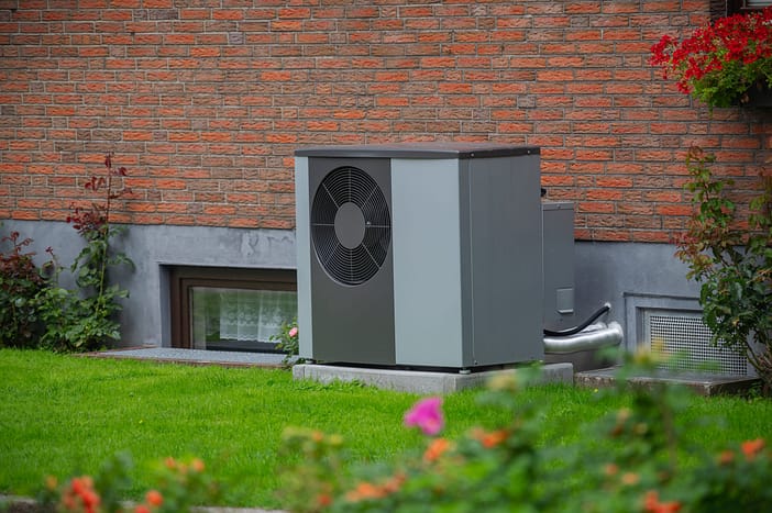Wärmepumpen-Außengerät Ein Wärmepumpen-Außengerät im Garten nahe der Hauswand