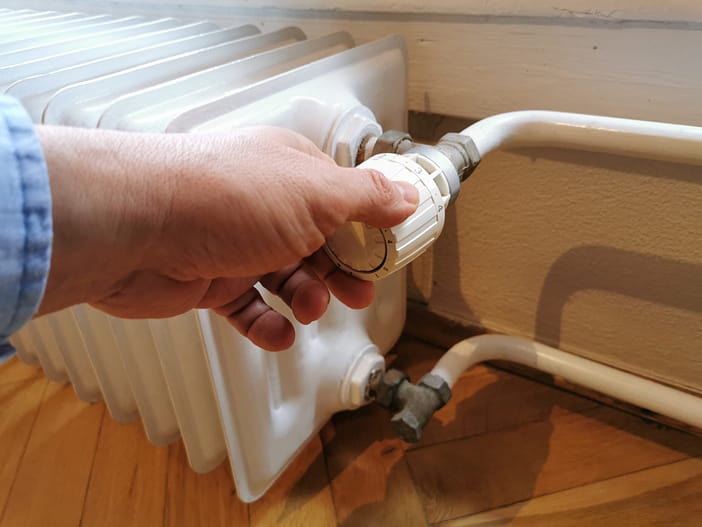 Hand am Thermostat eines alten Heizkörper im Altbau